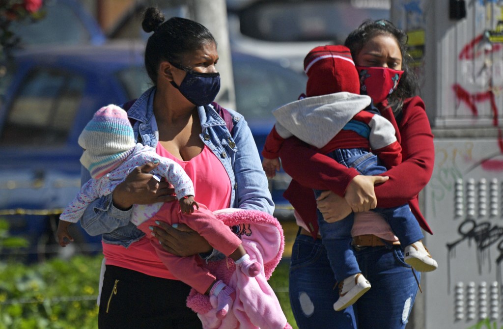Mujeres con tapabocas caminan por calles de Bogotá.
