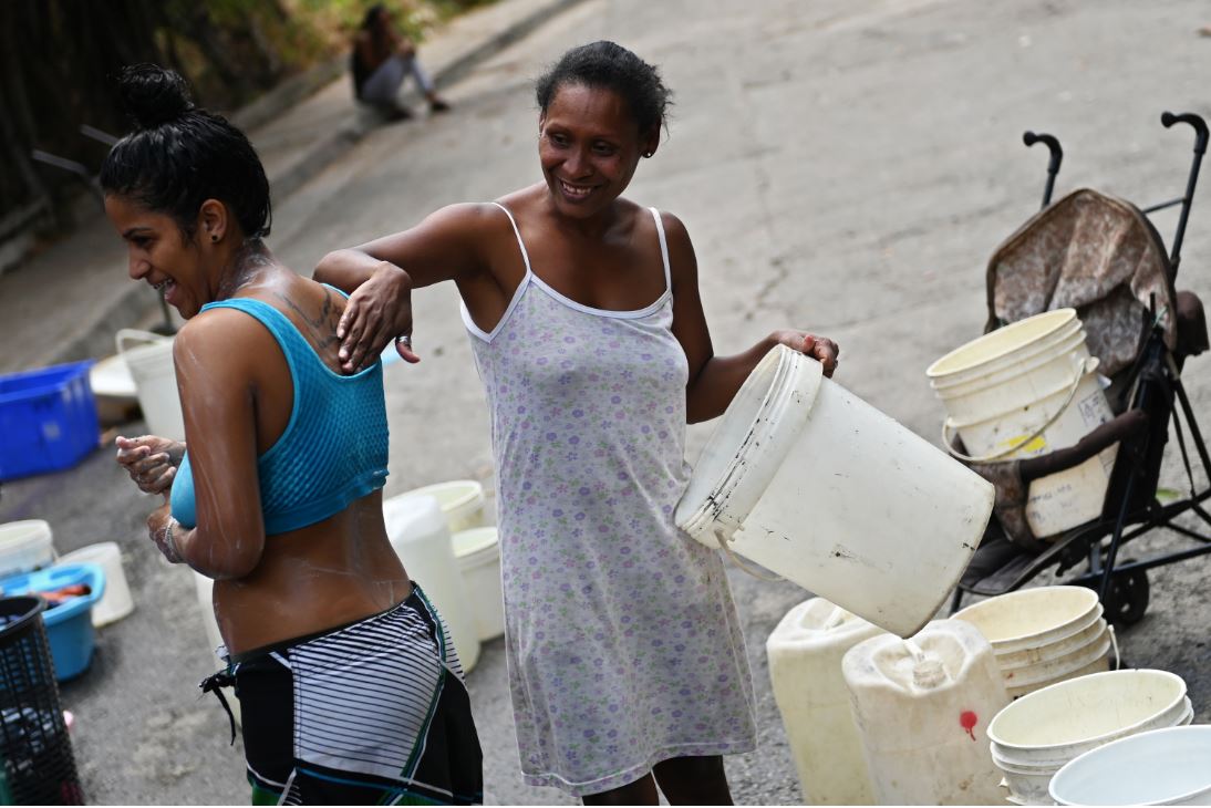 Dos mujeres se bañan en una calle de Caracas.