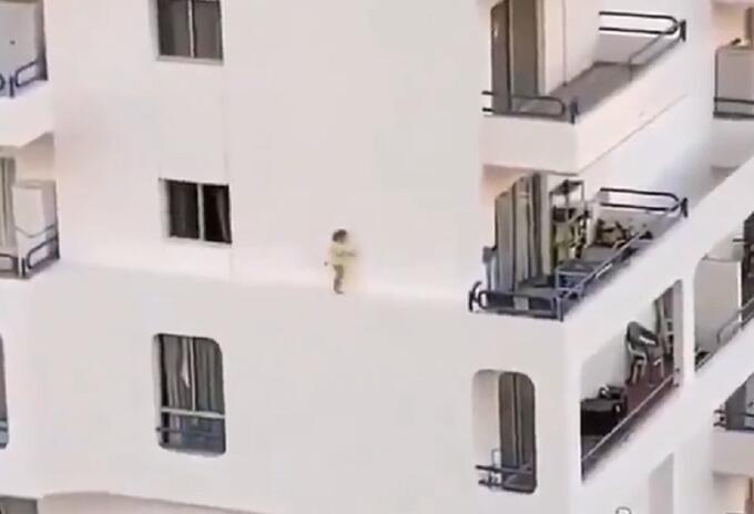 Niña caminando por el estrecho borde de un edificio