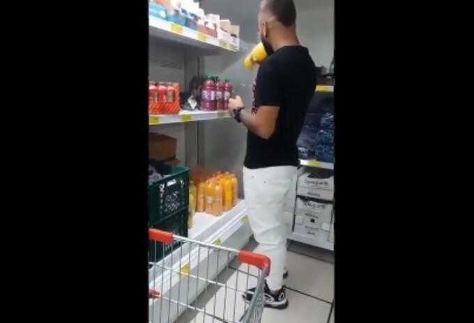Hombre tomando de varias botellas de jugo en supermercado de Medellín