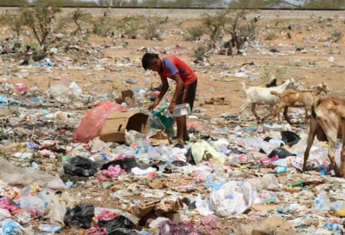 Niño indígena buscando alimentos entre la basura.