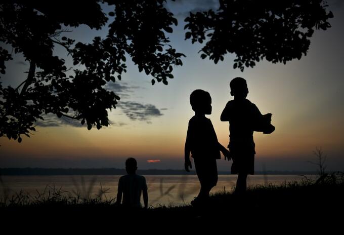 Silueta de niños indígenas, al pie del río Amazonas.