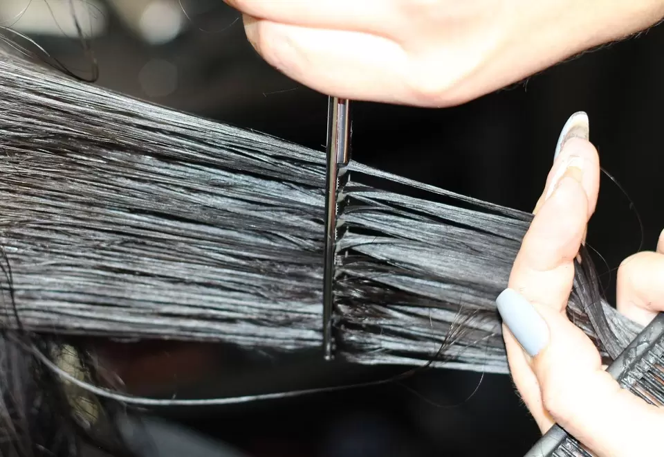Persona aplicando keratina en un cabello con un cepillo 