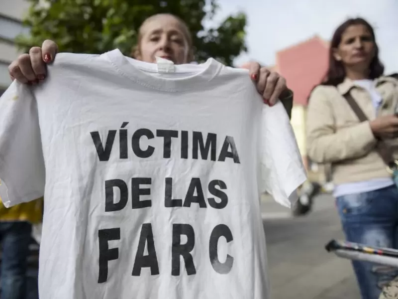 Una mujer sostiene una camiseta con la leyenda "Víctima de las Farc" durante una protesta afuera en la sede de la Jurisdicción Especial para la Paz (JEP) en Bogotá, el 13 de julio de 2018.