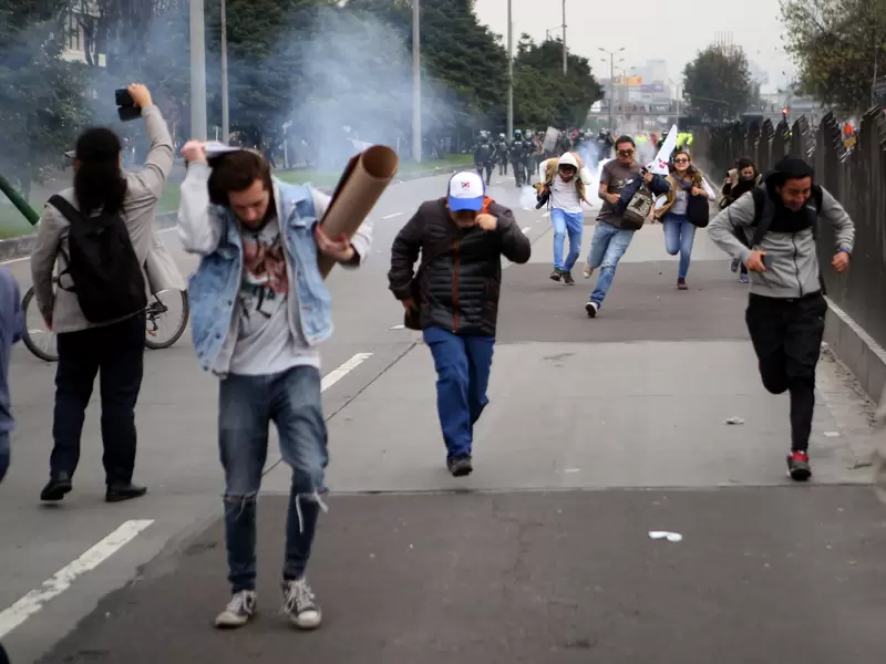 Varios estudiantes escapan de las bombas de aturdimiento del ESMAD