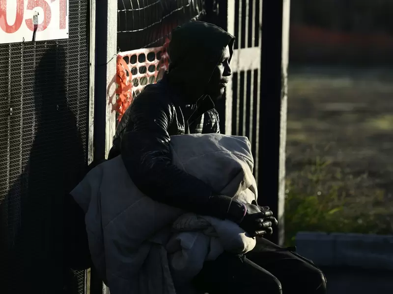 Un migrante que tiene una funda de edredón se sienta durante la evacuación de una antigua fábrica de penicilina donde los migrantes de África, pero también los italianos, vivían en condiciones precarias
