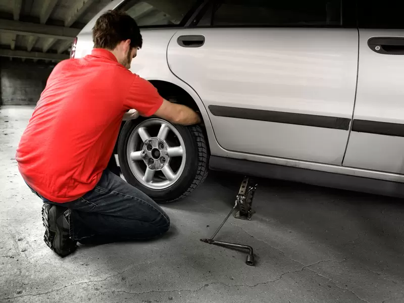 Un hombre cambiando una llanta de automóvil Un hombre cambiando una llanta de automóvil
