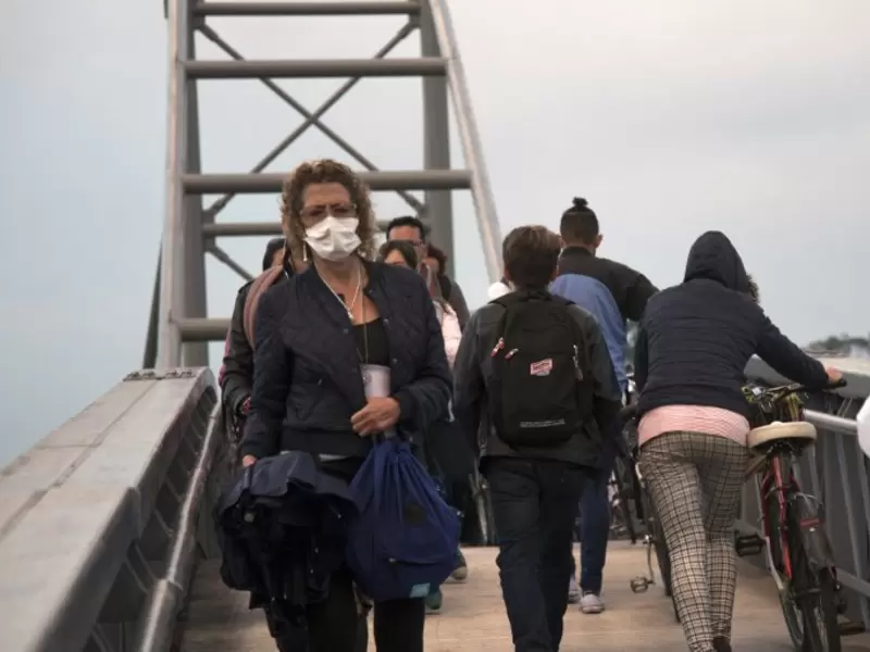 Una mujer con tapabocas camina en Bogotá. Mujer cruza puente peatonal con tapabocas, a raíz de la contaminación del aire