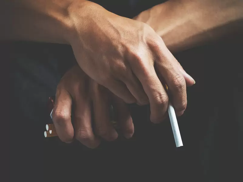 Un hombre sostiene cigarrillos en sus manos