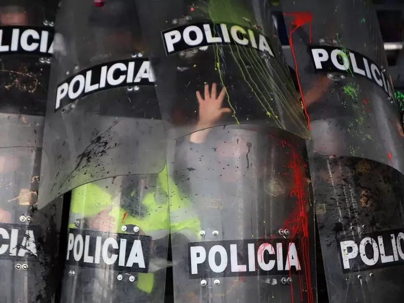 Policías del Esmad se protegen de vándalos en estación de Transmilenio.