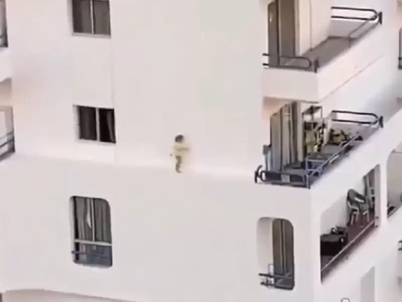 Niña caminando por el estrecho borde de un edificio