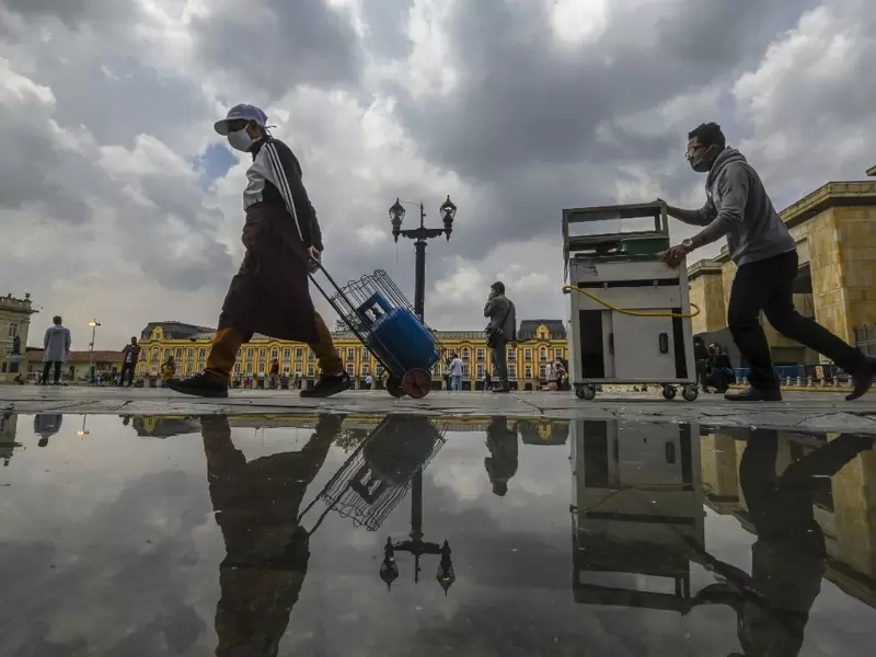 Vendedores ambulantes con tapabocas caminan en la plaza Bolívar, en Bogotá.