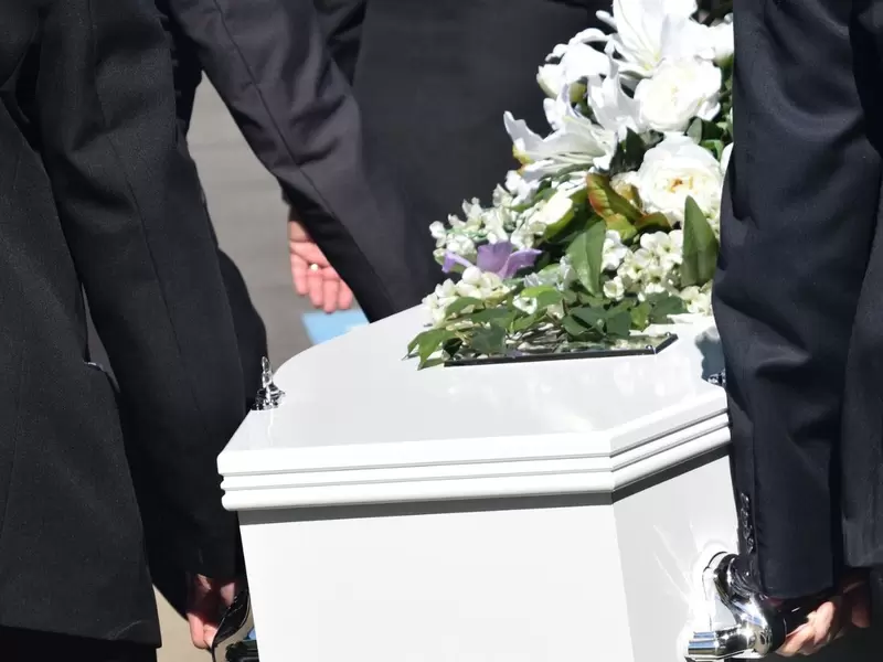 Hombres llevando un ataúd blanco